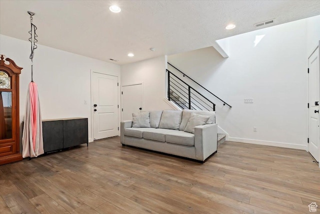 living room with recessed lighting, visible vents, stairway, and light wood finished floors