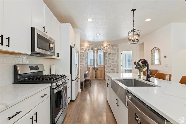 kitchen featuring hanging light fixtures, appliances with stainless steel finishes, a sink, and decorative backsplash