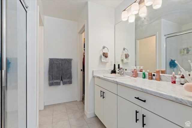 full bath with a stall shower, tile patterned floors, baseboards, and vanity