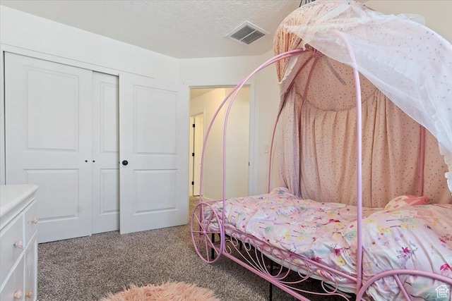 carpeted bedroom with a textured ceiling, a closet, and visible vents