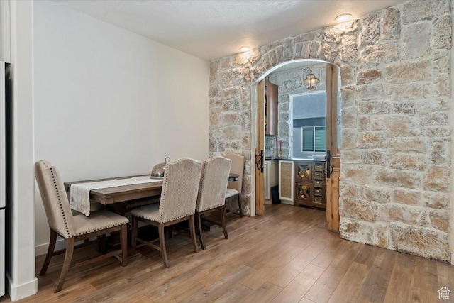 dining room featuring arched walkways and wood finished floors