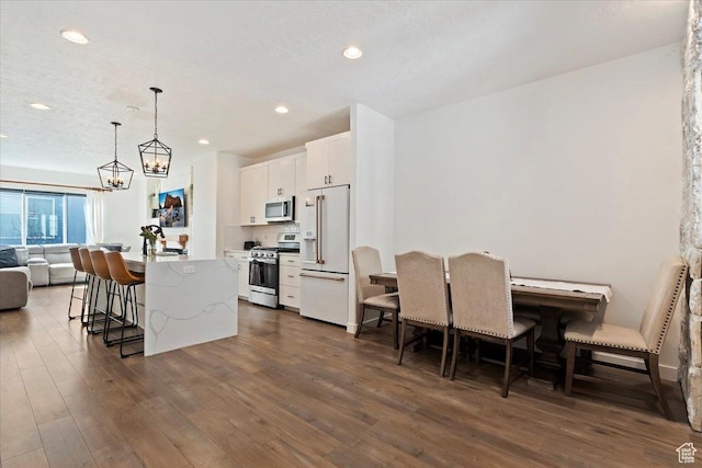 kitchen featuring dark wood-style floors, a breakfast bar area, appliances with stainless steel finishes, white cabinets, and a kitchen island