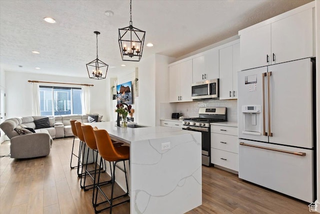kitchen featuring a breakfast bar area, stainless steel appliances, wood finished floors, open floor plan, and backsplash
