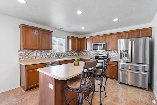 5906 Columbus Cir, Stansbury Park, UT 84074 - kitchen featuring appliances with stainless steel finishes, tasteful backsplash, light countertops, a sink, and a center island