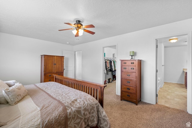 5906 Columbus Cir, Stansbury Park, UT 84074 - bedroom with a walk in closet, light colored carpet, a closet, a textured ceiling, and a ceiling fan