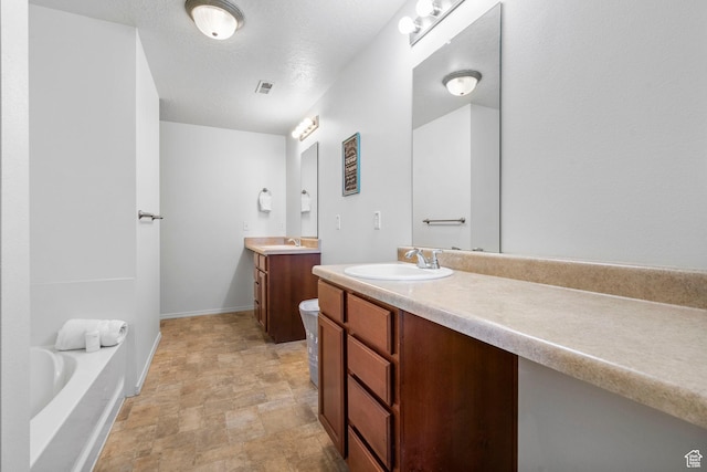 5906 Columbus Cir, Stansbury Park, UT 84074 - bathroom featuring two vanities, stone finish flooring, a bathtub, baseboards, and a textured ceiling