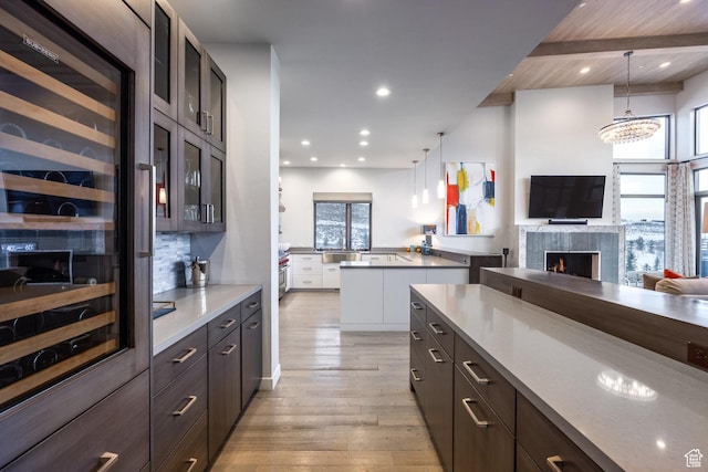 6379 W Golden Bear Loop, Park City, UT 84098 - kitchen with wine cooler, a fireplace, light wood-style flooring, glass insert cabinets, and open floor plan