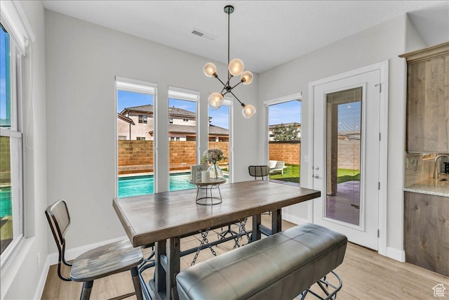 dining area featuring a chandelier, light wood-type flooring, visible vents, and baseboards