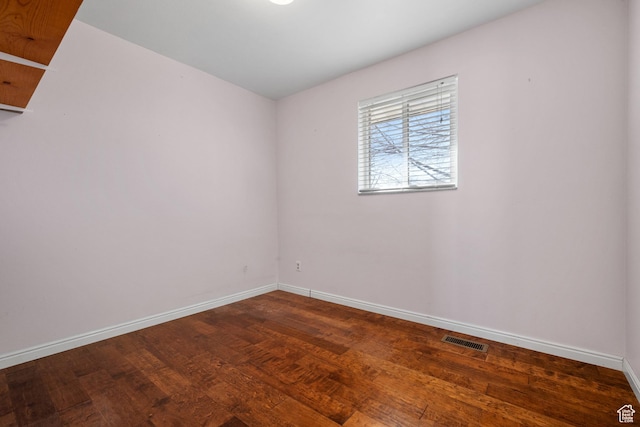 empty room featuring visible vents, baseboards, and wood finished floors