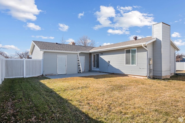 rear view of property featuring a patio, a lawn, a chimney, and fence