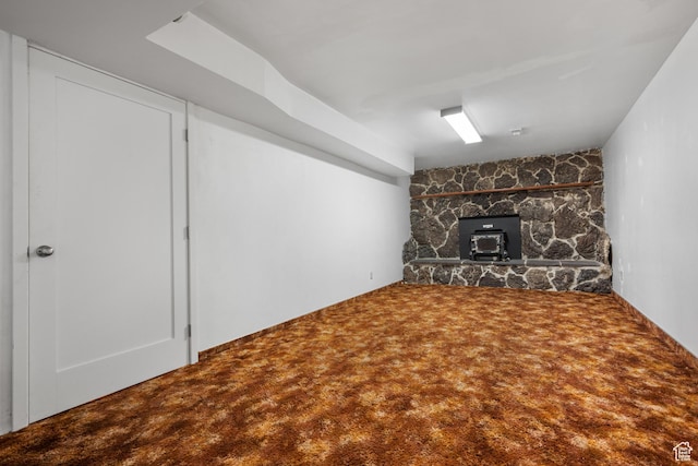 unfurnished living room featuring a wood stove and carpet flooring