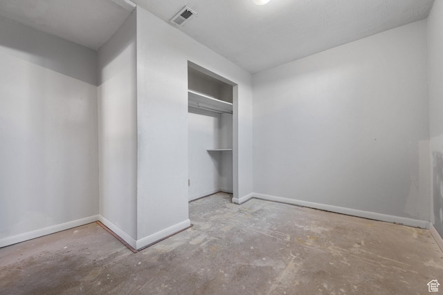 unfurnished bedroom with a closet, visible vents, unfinished concrete flooring, and baseboards