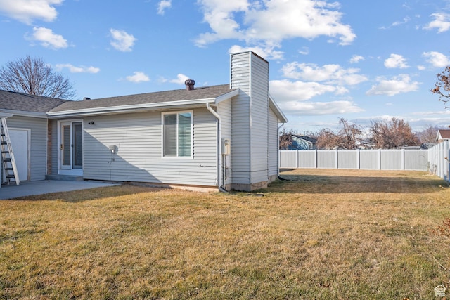 back of house with a patio area, a chimney, fence, and a yard