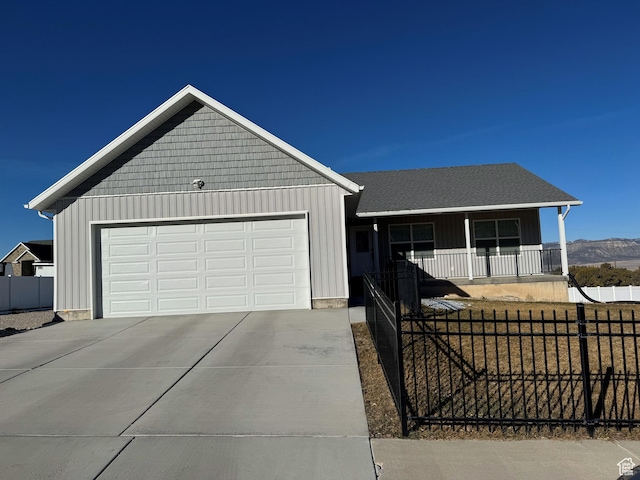 ranch-style house featuring a fenced front yard, a porch, concrete driveway, board and batten siding, and a garage