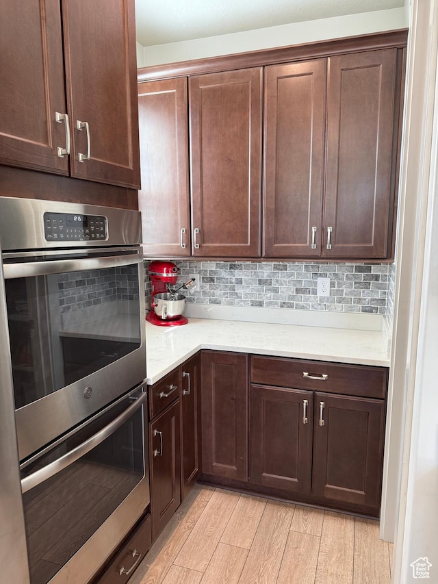 6274 N Vernon Dr E, Eagle Mountain, UT 84005 - kitchen featuring light countertops, stainless steel double oven, light wood-type flooring, and decorative backsplash