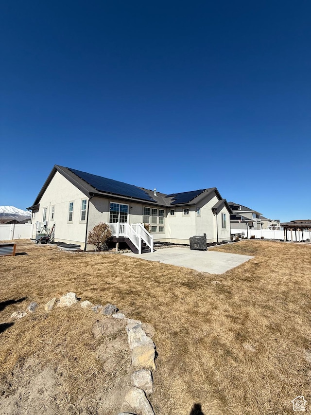 6274 N Vernon Dr E, Eagle Mountain, UT 84005 - back of house with a patio area, stucco siding, solar panels, and a yard