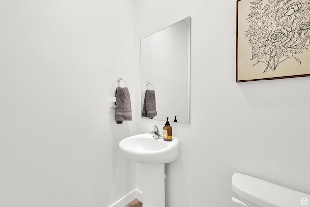 half bath with baseboards and toilet
