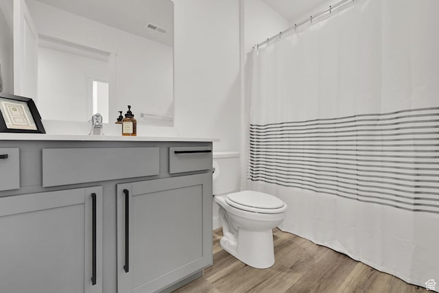 full bathroom with a shower with curtain, vanity, toilet, visible vents, and wood finished floors