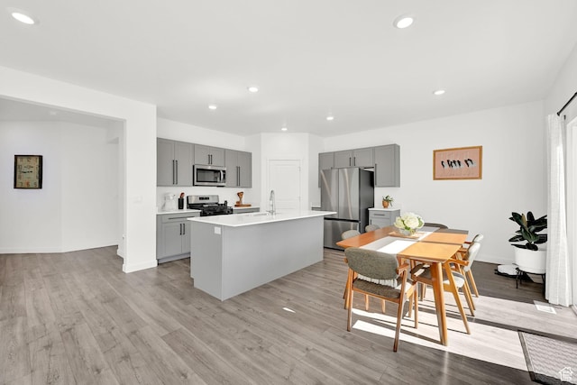 kitchen featuring gray cabinetry, light wood-type flooring, light countertops, and appliances with stainless steel finishes