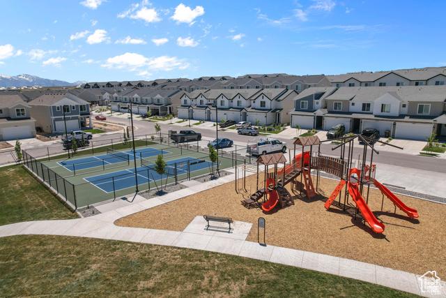 communal playground with a tennis court, fence, and a residential view