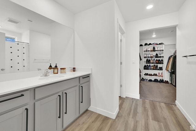 bathroom featuring visible vents, a walk in closet, vanity, and wood finished floors