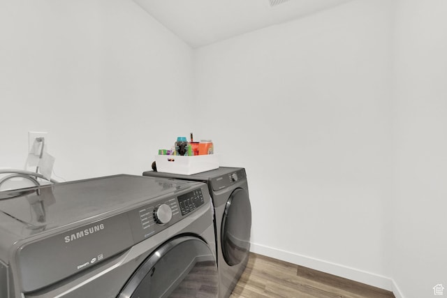 laundry area with baseboards, wood finished floors, laundry area, and separate washer and dryer