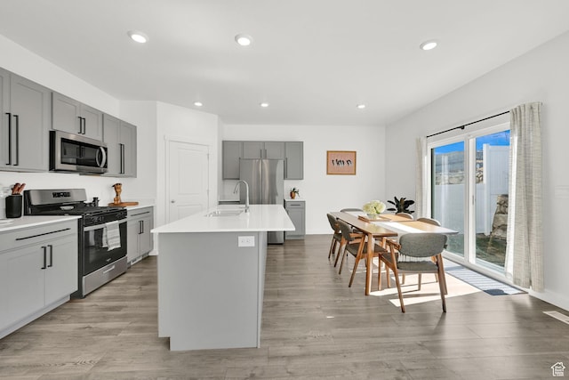 kitchen with light countertops, stainless steel appliances, a sink, light wood-style floors, and gray cabinets