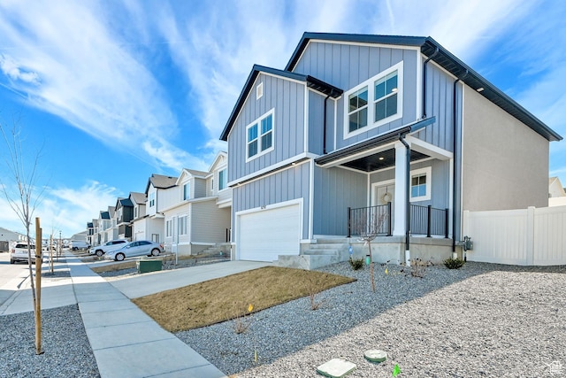 view of front of property featuring an attached garage, board and batten siding, a residential view, driveway, and covered porch