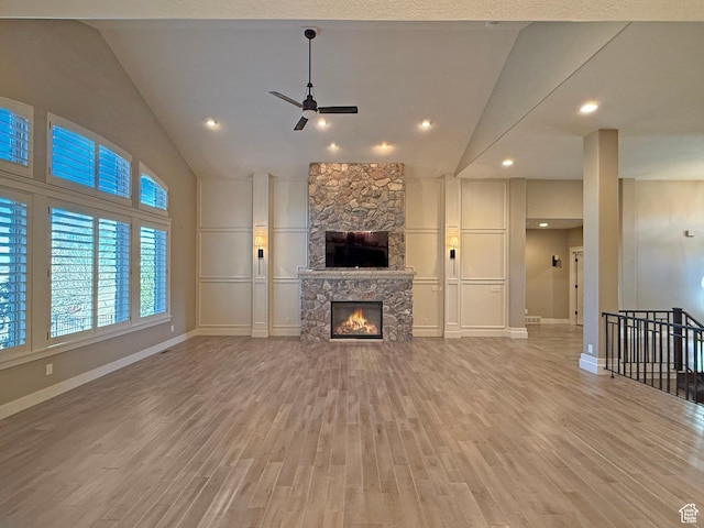 1663 N 3500 W, Plain City, UT 84404 - unfurnished living room with light wood-style floors, ceiling fan, vaulted ceiling, and a stone fireplace