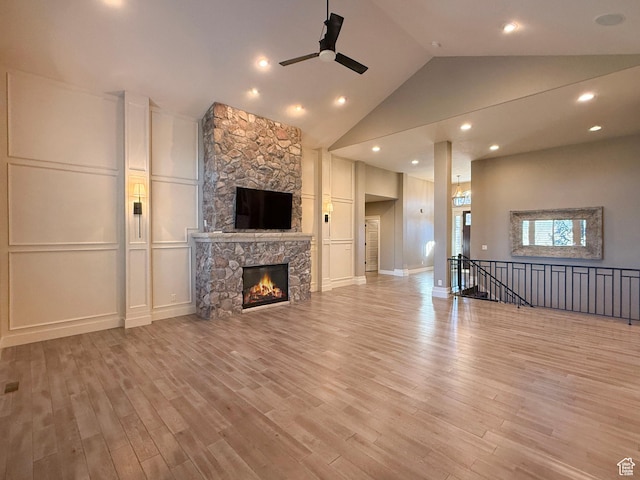 1663 N 3500 W, Plain City, UT 84404 - unfurnished living room featuring a decorative wall, a ceiling fan, a stone fireplace, high vaulted ceiling, and light wood-type flooring