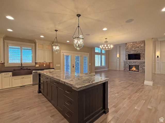 1663 N 3500 W, Plain City, UT 84404 - kitchen featuring a stone fireplace, a sink, light wood-style flooring, and tasteful backsplash