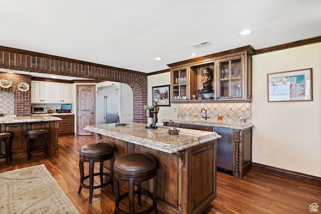 1698 S Amanda Ln E, Saratoga Springs, UT 84045 - kitchen featuring visible vents, dark wood finished floors, glass insert cabinets, a center island, and crown molding