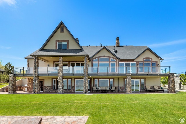 back of house featuring a yard, a patio area, a balcony, and stucco siding