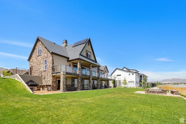 1698 S Amanda Ln E, Saratoga Springs, UT 84045 - rear view of property with a chimney, stone siding, a lawn, and a balcony