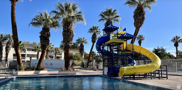 pool featuring playground community, fence, and a water slide