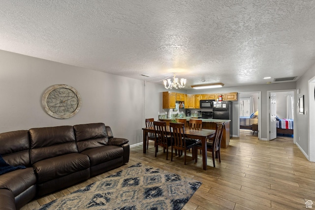 living area featuring baseboards, light wood finished floors, visible vents, and a notable chandelier