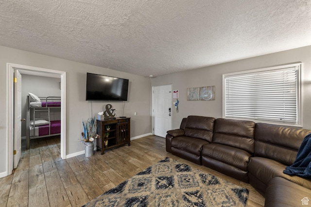 living area with a textured ceiling, hardwood / wood-style flooring, and baseboards