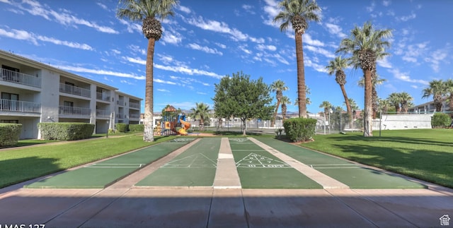surrounding community featuring shuffleboard, a yard, playground community, and fence