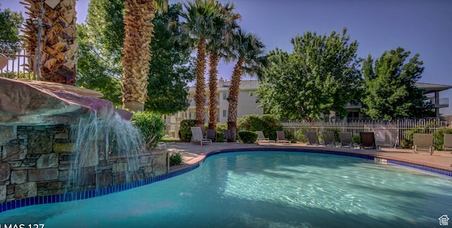 pool with a patio area and fence