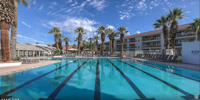 community pool featuring a residential view, a patio area, and fence