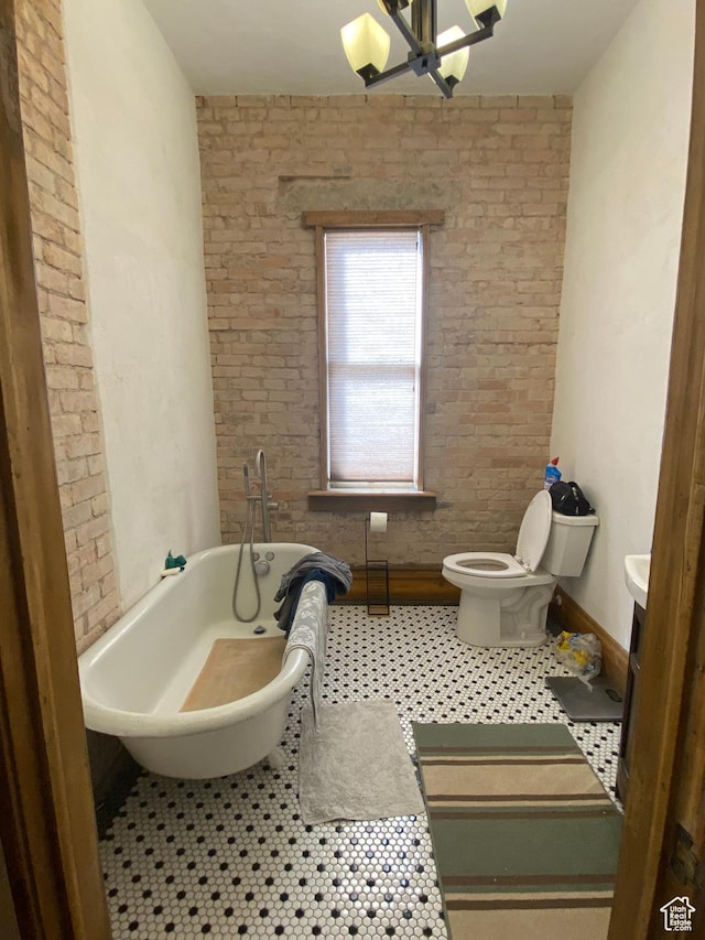 full bathroom with toilet, a notable chandelier, a freestanding bath, and tile patterned floors