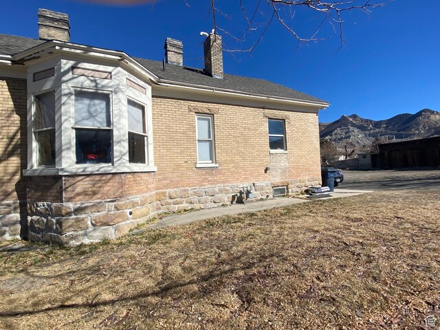 view of side of home with brick siding, a chimney, and a mountain view