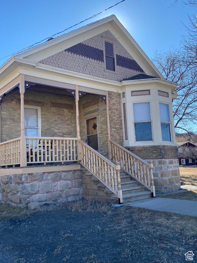 view of front of home featuring covered porch and brick siding