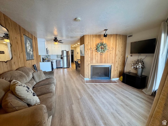 2176 S Bear Blvd Unit 316, & Garden City, UT 84028 - living room featuring a textured ceiling, light wood-type flooring, wood walls, and a fireplace