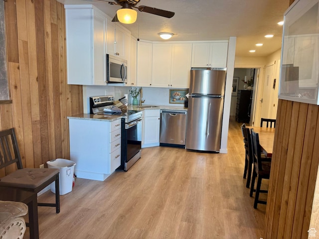 2176 S Bear Blvd Unit 316, & Garden City, UT 84028 - kitchen with ceiling fan, wooden walls, white cabinetry, light wood-style floors, and appliances with stainless steel finishes