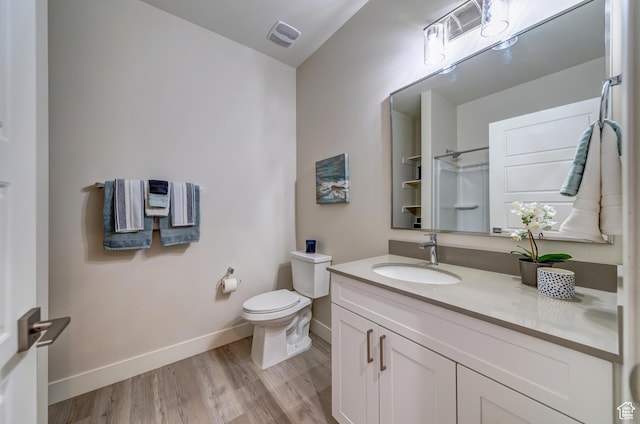 bathroom featuring wood finished floors, visible vents, toilet, vanity, and baseboards