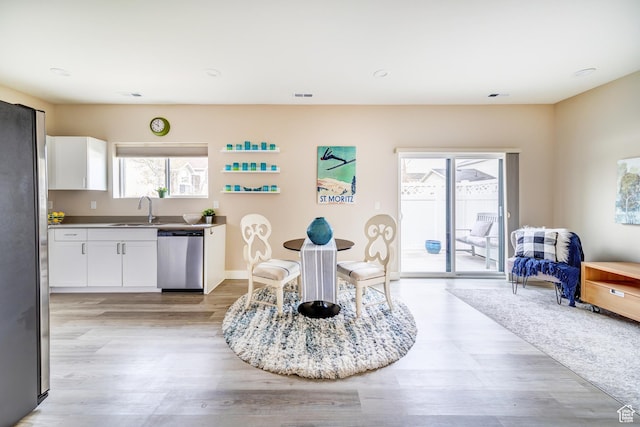 dining area featuring light wood-style flooring, a wealth of natural light, and baseboards