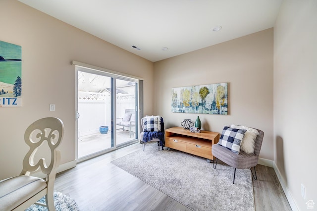 sitting room with wood finished floors, visible vents, and baseboards