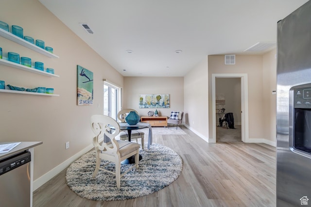 living area with baseboards, visible vents, and light wood-style floors