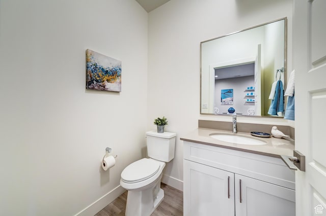 bathroom featuring baseboards, wood finished floors, toilet, and vanity